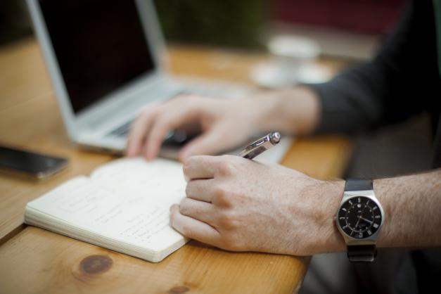 Hands writing in notebook at desk