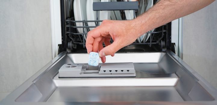 Hand putting dishwasher tab in dishwasher