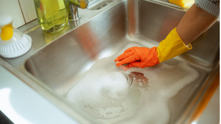 gloved hand cleaning the kitchen sink