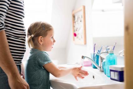 Woman helping child wash hands
