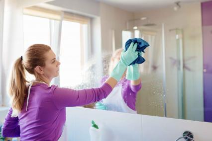 Woman wiping down the bathroom mirror